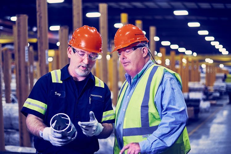 Men in hard hats talking and evaluating mechanical part