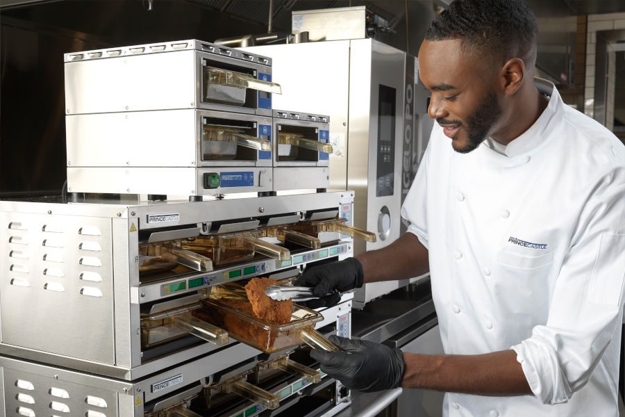 Foodservice-Technologies-Holding-Prince-Castle-900x600 Male kitchen worker pulling food out from under equipment