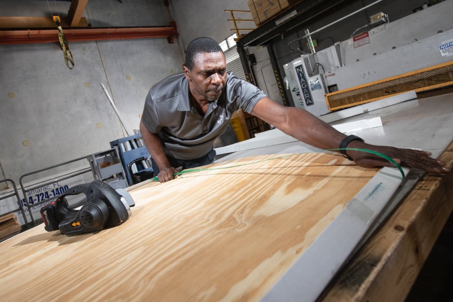 Male employee measuring word before cutting with saw