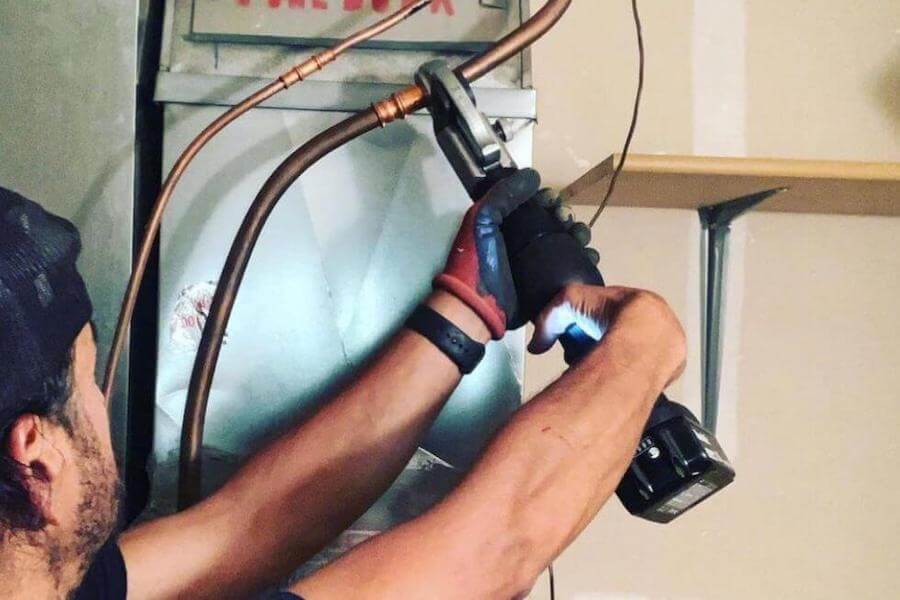 Plumber working on copper pipe with a wrench.