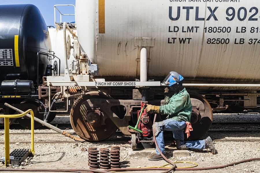 Employee servicing tank car Union Tank Car outside wearing protective gear