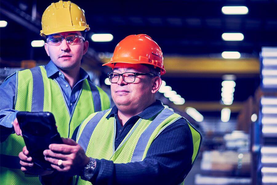 two men in hard hats collaborating on tablet