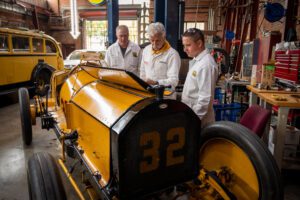 Two of the Marmon Wasp Engineers standing by a replica Marmon Wasp with Corky Coker at Honest Charley 